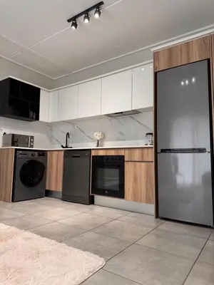 a kitchen with white cabinets and a black dishwasher at Staycation At Munyaka Estate in Midrand