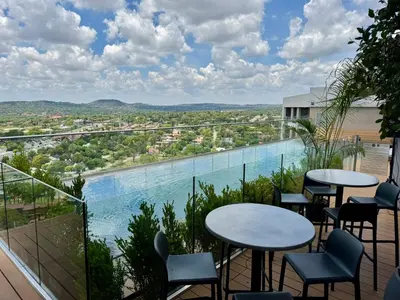 a balcony with tables and chairs and a swimming pool at Menlyn Maine Residences 811 in Pretoria