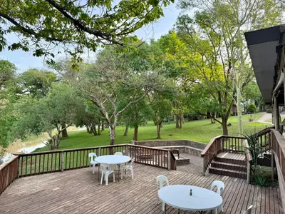 a deck with tables and chairs and a park at Elephant 1 Chalet Hippo Waterfront Lodge in Nelspruit