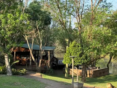 a cabin in the middle of a yard with trees at Elephant 1 Chalet Hippo Waterfront Lodge in Nelspruit