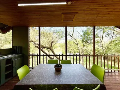 a dining room with a table and green chairs at Elephant 1 Chalet Hippo Waterfront Lodge in Nelspruit