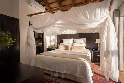 a bedroom with a white canopy bed with pillows at Karongwe- Shiduli Safari Lodge in Hoedspruit
