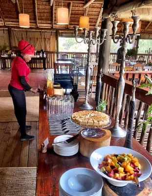 a woman standing in front of a table with food at Karongwe - Chisomo Safari Camp in Hoedspruit