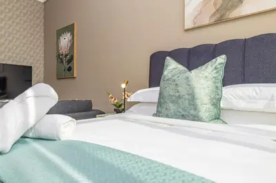 a white bed with a green pillow on it at StayCeity at Menlyn Maine in Pretoria
