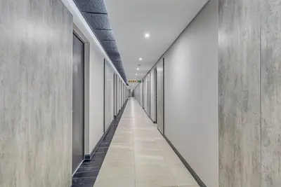 a corridor in a building with white walls and a long hallway at StayCeity at Menlyn Maine in Pretoria