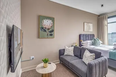 a living room with a couch and a bed at StayCeity at Menlyn Maine in Pretoria