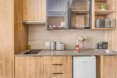 a kitchen with wooden cabinets and a counter top at StayCeity at Menlyn Maine in Pretoria