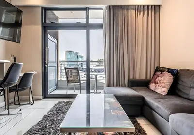 a living room with a couch and a glass table at Menlyn Maine Residences 813 in Pretoria