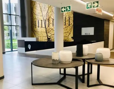 two tables and chairs in a lobby with a wall at Menlyn Maine Residences 813 in Pretoria