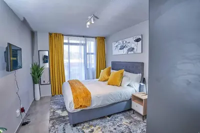 a bedroom with a bed with yellow curtains and a window at Spacious Fully Equipped Studio - Peaceful-Free WiFi in Pretoria