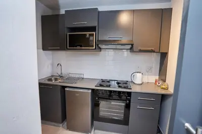 a kitchen with stainless steel appliances and black cabinets at Spacious Fully Equipped Studio - Peaceful-Free WiFi in Pretoria