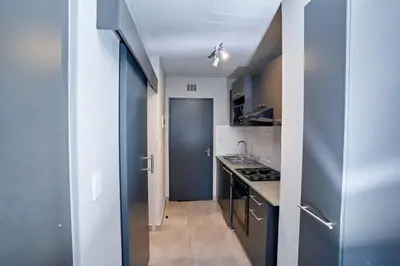 a small kitchen with a blue door and a hallway at Spacious Fully Equipped Studio - Peaceful-Free WiFi in Pretoria