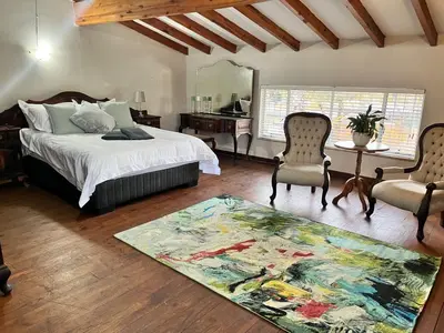 a bedroom with a bed and two chairs and a rug at Grace541 in Pretoria