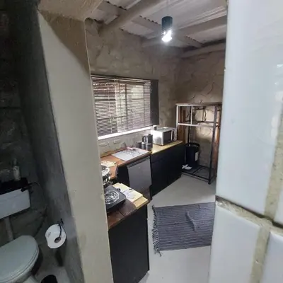 a room with a kitchen with a sink and a toilet at Wegpak in Barberton