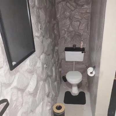 a stone bathroom with a toilet and a tv at Wegpak in Barberton