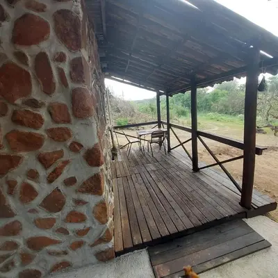 a wooden deck with a stone wall and tables at Wegpak in Barberton