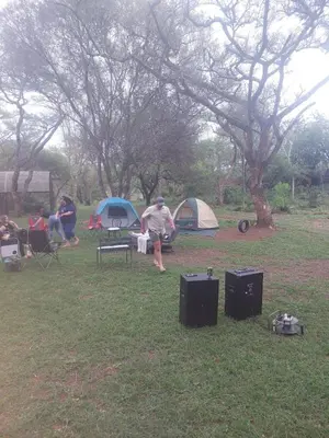 a group of people sitting in the grass near tents at Sak n pak Kamp in Barberton