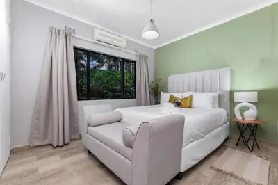 a bedroom with a white bed and a chair at Bird of Paradise in Tzaneen