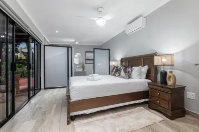 a bedroom with a large bed and glass windows at Bird of Paradise in Tzaneen