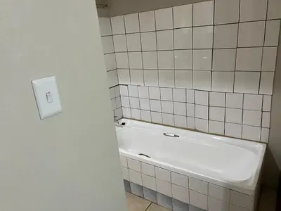 a white bath tub in a bathroom with white tiles at Zonke Bonke Guest House Lydenburg in Lydenburg