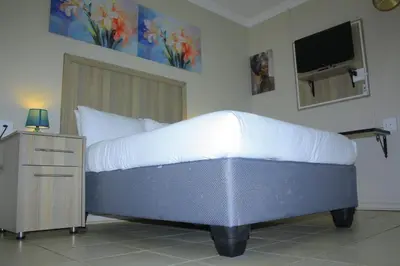 a bedroom with a bed with a tv on the wall at Zonke Bonke Guest House Lydenburg in Lydenburg