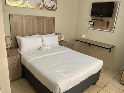 a bedroom with a large bed with white sheets at Zonke Bonke Guest House Lydenburg in Lydenburg