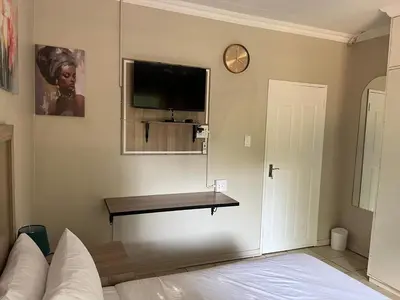 a bedroom with a bed and a tv on the wall at Zonke Bonke Guest House Lydenburg in Lydenburg