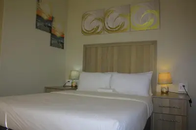a bedroom with a large white bed with two lamps at Zonke Bonke Guest House Lydenburg in Lydenburg