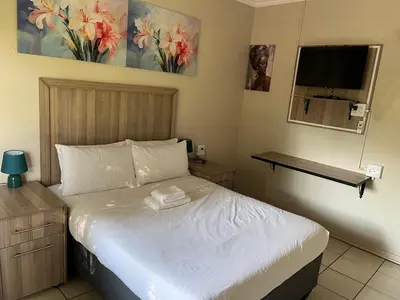 a bedroom with a bed and a television in it at Zonke Bonke Guest House Lydenburg in Lydenburg