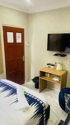 a bedroom with a bed and a flat screen tv at Crown Palace Guesthouse in Pretoria