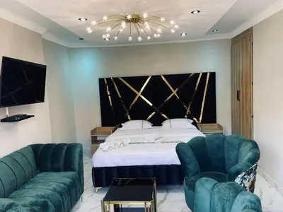 a bedroom with a bed and two green chairs at Crown Palace Guesthouse in Pretoria