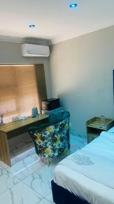 a bedroom with a bed and a desk and a chair at Crown Palace Guesthouse in Pretoria