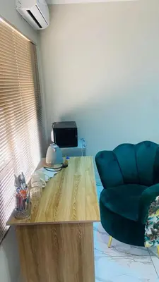 a living room with a wooden table and a green chair at Crown Palace Guesthouse in Pretoria