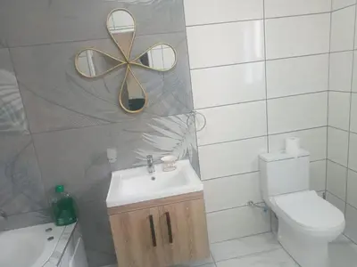 a bathroom with a sink and a toilet and a mirror at Crown Palace Guesthouse in Pretoria