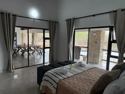 a bedroom with a bed and a living room at Elephant Rest in Marloth Park