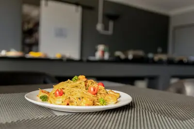 a plate of pasta with tomatoes on a table at Khayalami Hotel - Secunda in Secunda