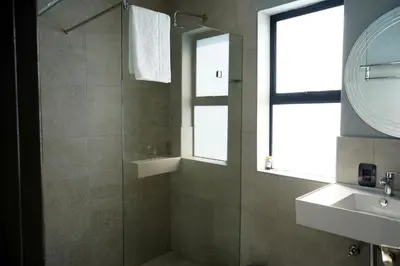 a bathroom with a shower and a sink and a mirror at Khayalami Hotel - Secunda in Secunda