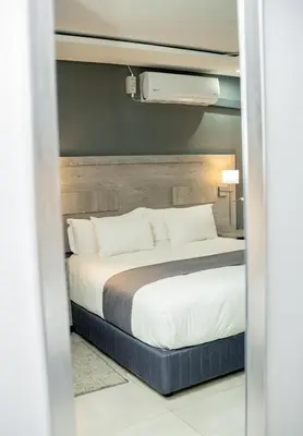 a bedroom with a large bed with white sheets at Khayalami Hotel - Secunda in Secunda