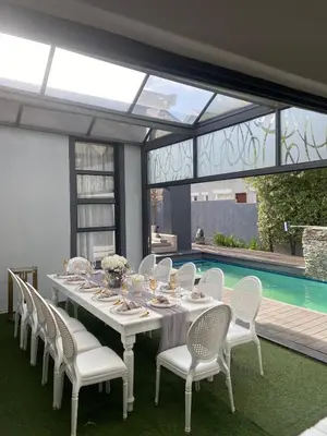 a dining table with white chairs and a pool at oliphant private House in Midrand