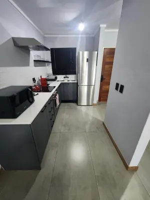 a kitchen with a refrigerator and a counter top at Vista Retreat - Stylish Flat at Menlyn Main in Pretoria