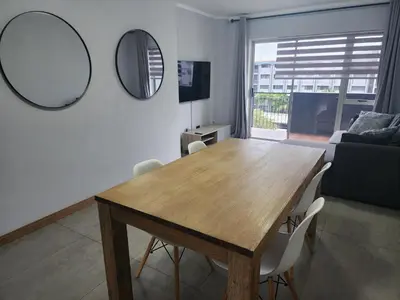 a living room with a wooden table and two mirrors at Vista Retreat - Stylish Flat at Menlyn Main in Pretoria