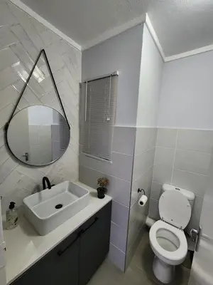 a bathroom with a sink and a toilet and a mirror at Vista Retreat - Stylish Flat at Menlyn Main in Pretoria