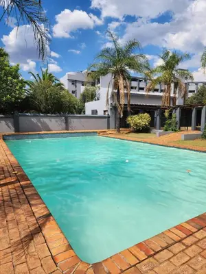a swimming pool with blue water in front of a building at Vista Retreat - Stylish Flat at Menlyn Main in Pretoria
