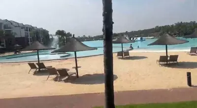 a beach with chairs and umbrellas in front of a pool at The Blyde Crystal Lagoon in Pretoria