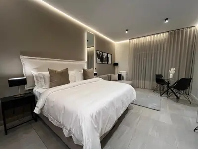 a bedroom with a large white bed and a table at Luxury King Studio, Menlyn Maine, Time Square Views, Smart Access in Pretoria