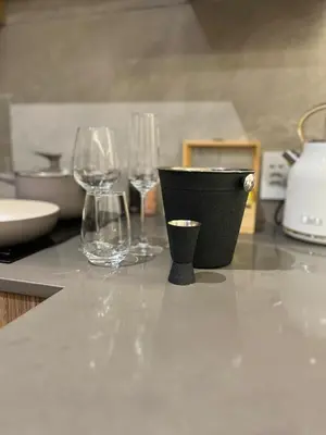 three wine glasses and a black pot on a counter at Luxury King Studio, Menlyn Maine, Time Square Views, Smart Access in Pretoria
