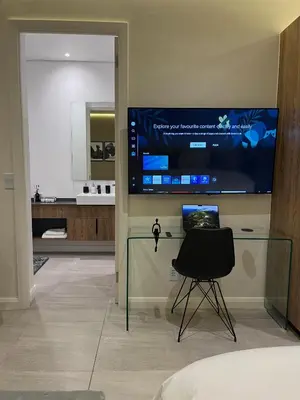a bedroom with a desk with a chair and a television at Luxury King Studio, Menlyn Maine, Time Square Views, Smart Access in Pretoria