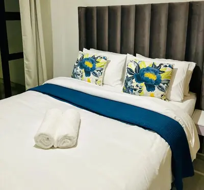 a white bed with blue and yellow flowers on it at DreamStay The Blyde Pretoria in Pretoria