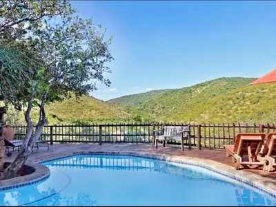 a swimming pool with two chairs and a fence at Mabalingwe in Bela-Bela
