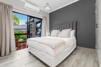 a bedroom with a white bed and a large window at Honeysuckle in Tzaneen